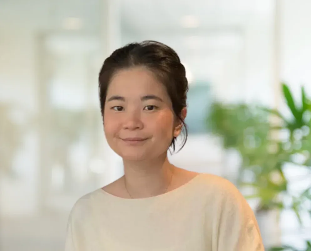 A portrait of Alice, Operations Manager, in an office with plants behind her.