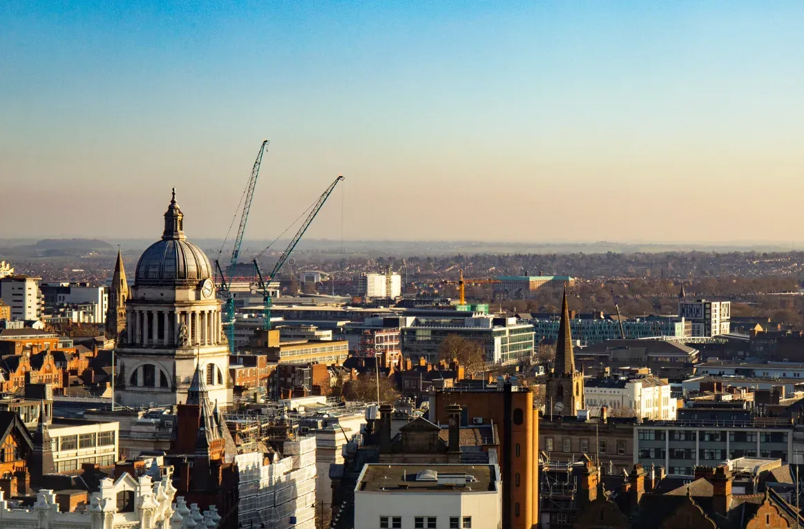 Nottingham's skyline at golden hour, the Council House dome among cranes and rooftops.