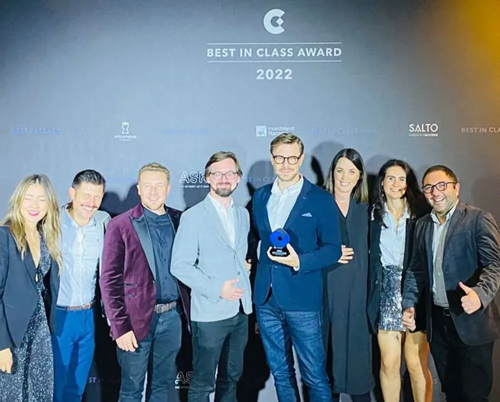 Eight people on stage holding a trophy, the backdrop reading Best in Class Award 2022.
