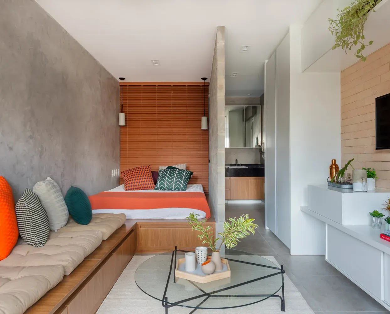 A compact studio apartment with a bed, a sofa and a kitchenette along one wall.